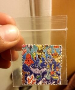 Colorful rainbow-printed LSD blotter paper sheet with cartoon character perforated artwork