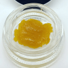 Blue Dream live resin concentrate showing golden amber texture in a small glass container, sativa-dominant high THC cannabis extract