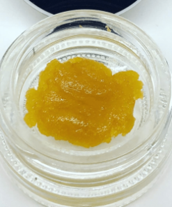 Blue Dream live resin concentrate showing golden amber texture in a small glass container, sativa-dominant high THC cannabis extract