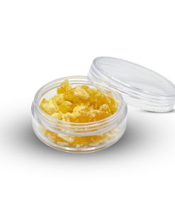 Golden crumble cannabis concentrate with dry, crumbly texture on a flat surface
