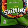 Colorful Skittles candy pouch with rainbow candies spilling out.